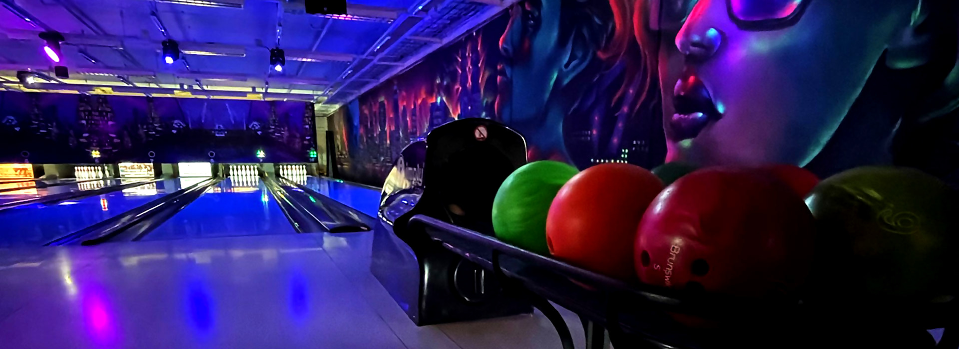 Åsane Bowling & Eventsenter — selvlysende bowlingbaner med neon-veggmaleri og ball-retur i forgrunnen