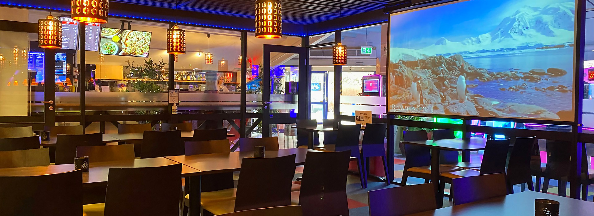 Spise- og barområdet hos Åsane Bowling — varme lampeskjermer og bord langs baren
